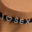 A close up of a black choker worn around a mannequin’s neck with the letters I heart sex on it encrusted with diamanté’s.