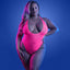 A plus-size model poses in a neon pink net teddy in a black light setting to show the teddy's glow-in-the-dark properties.