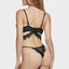 Back view of a model wearing a black eyelash lace bra and panty that features a criss-cross detail on the thong rear.