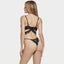 Back view of a model wearing a black bra and panty with draped lace trim around the adjustable hook-&-eye closure.