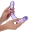 A hand model holds a realistic double-ended clear jelly dildo in purple showcasing its flexibility.  