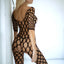 A model wears a holey black bodystocking with 3/4 sleeves and black g-string underneath. 