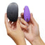 A model holds a purple We-Vibe Sync Go Couples Vibrator and the subtle travel case it comes with in both hands.