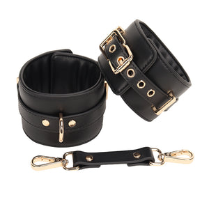 Black leather wrist cuffs with gold hardware & connection tether shown on a white background