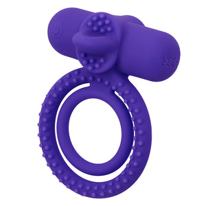 A purple dual cock & ball vibrating ring stands on a white backdrop showcasing its tongue-like stimulator. 