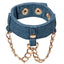A denim handcuff sits against a white backdrop and features draping gold chains.