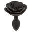 A large black silicone butt plug with a rose design base stands against a white backdrop.