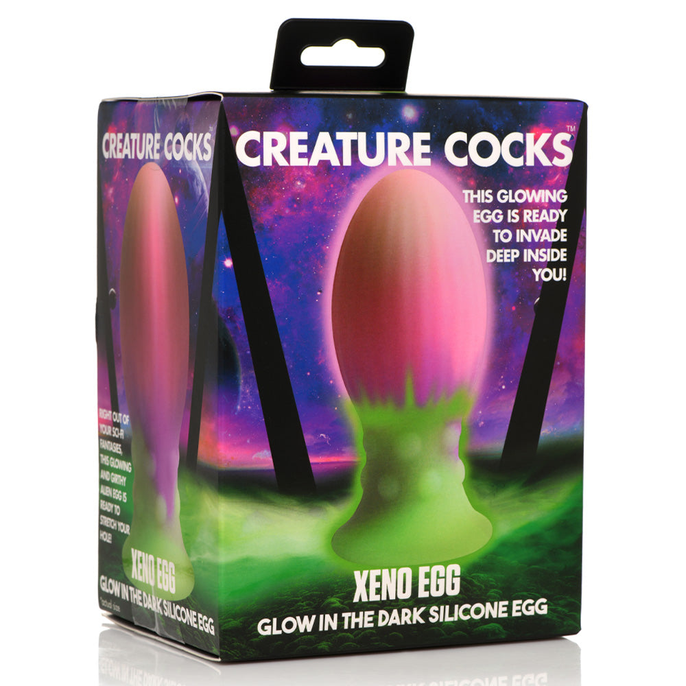 A box sits against a white backdrop with the Creature Cocks Xeno glow-in-the-dark egg plug on the front of it.
