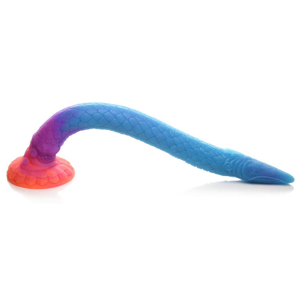A glow-in-the-dark sea snake dildo lays on its side, showing its scaly texture while anchored by its suction cup.