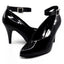 A pair of Ellie Shoes wide-fit black patent pumps with silver buckles on the ankle strap sits against a white backdrop.