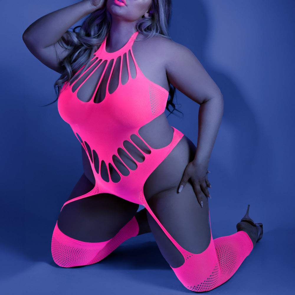 Plus size model wears a glow in the dark pink bodystocking teddy with fishnet weave and keyhole shredding over the bust.