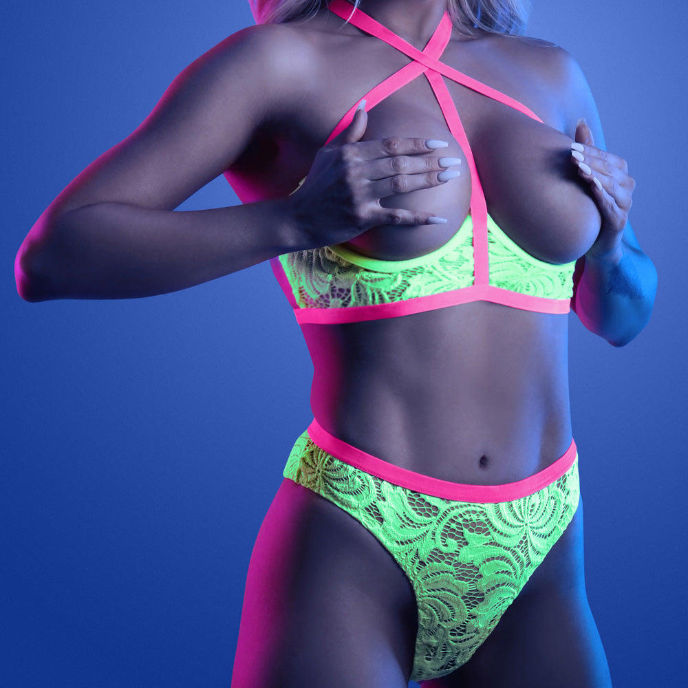A lingerie model wears a glow-in-the-dark floral lace cupless bra with underwire support and matching high-waisted panties.
