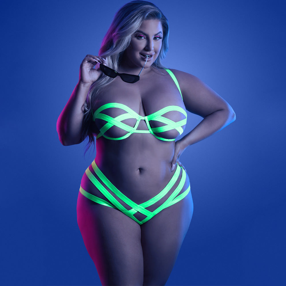 A curvy model wears a glow-in-the-dark neon green lingerie set with an open cage, crotchless panty and bandage-style bra.