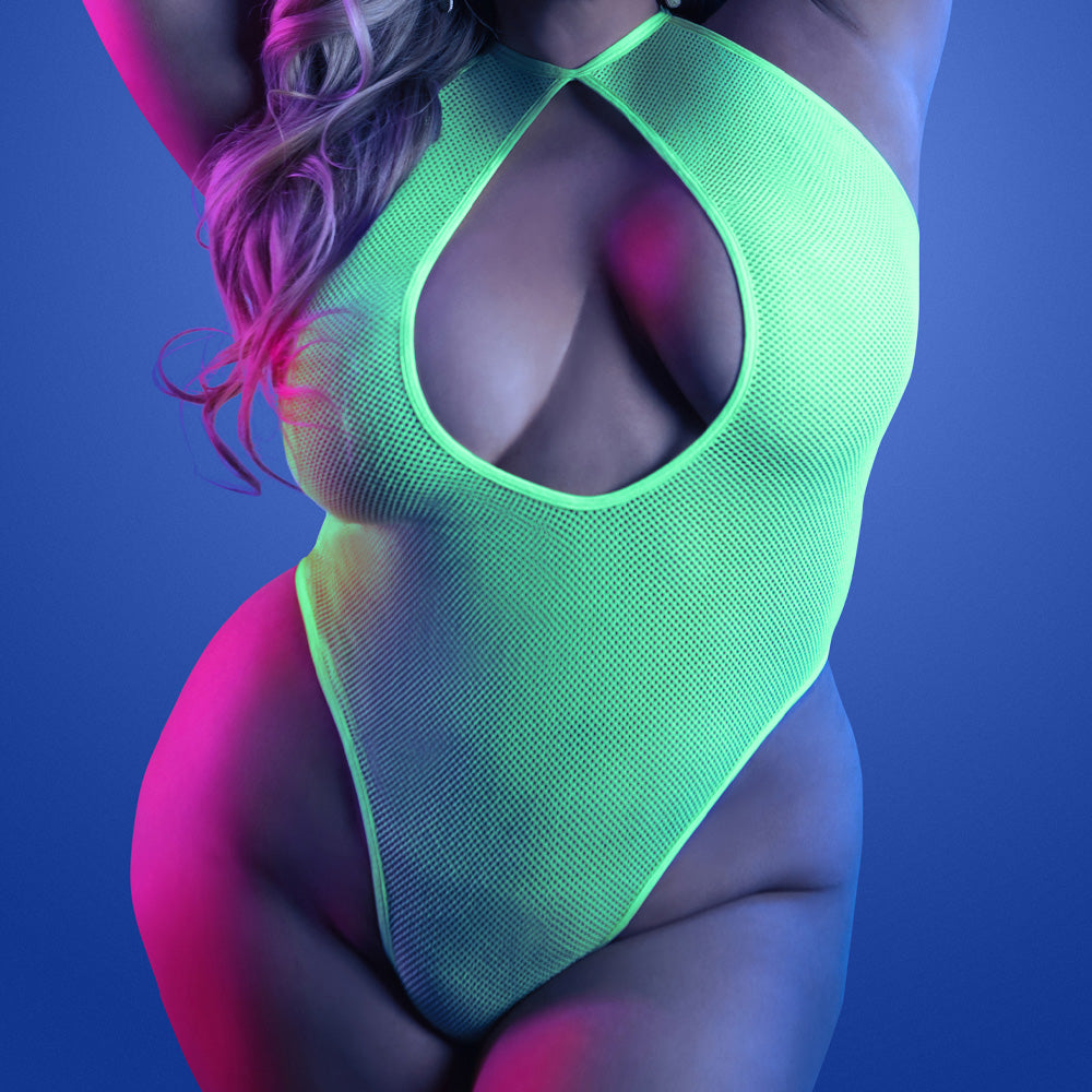 A plus size model wears a neon green glow in the dark fishnet weave teddy with a keyhole cutout at the bust.