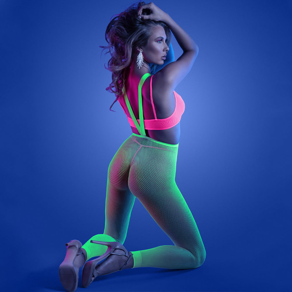 Back view of a model wearing a three-piece glow-in-the-dark neon green high-waisted footless fishnet stockings with heels.