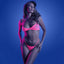 A model stands against a black light background wearing a neon pink fishnet bralette with a matching high-waisted G-string.