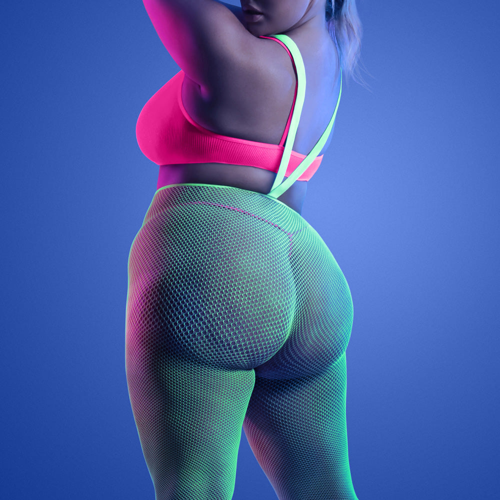 Back view of a plus size model wearing green fishnet suspender stockings with a neon pink bra and thong underneath.
