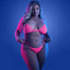 A plus-size model stands against a black light background wearing a neon pink fishnet bralette with high-waisted G-string.