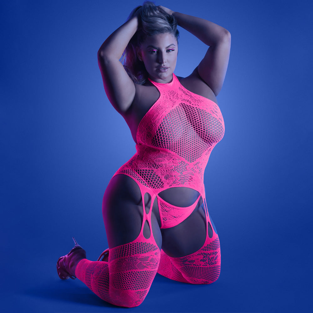 A plus-size model wears a neon pink bodystocking with a candy cane stripe pattern of alternating lace and net on the legs.