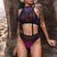 A model wears a sheer iridescent indigo and violet mesh halter top with shoulder suspenders attached to the panty waistband.
