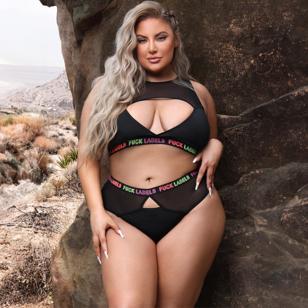 A plus size model wears a black crop bra and panty with a combo of sheer mesh and microfibre material.