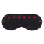 Flatlay of a black faux leather eye mask shows its contrast red stitching around the edge of the mask and red cutout hearts.