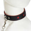 A mannequin wears a black faux leather collar with cutout red hearts all around it and a silver chain leash attached.