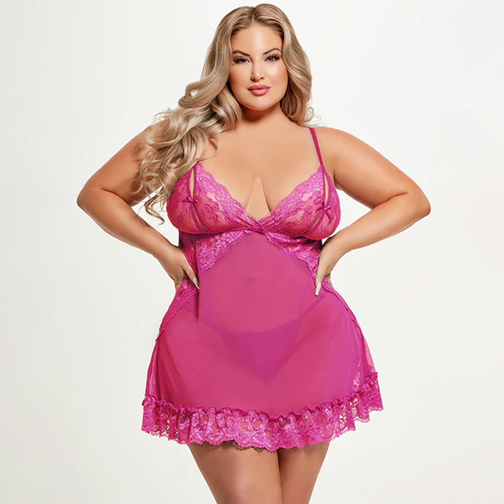 A curvy model wears a sheer pink babydoll with triangular lace overlay underneath the bust and a lace thong.
