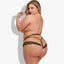 Back view of a plus-size lingerie model wearing a high-cut lace thong with strappy cutouts to reveal more skin.