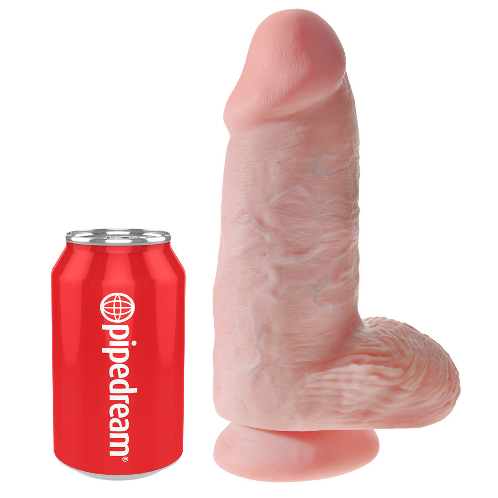 A realistic 9 inch veiny chubby dildo stands against a can by Pipedream showcasing the scale.
