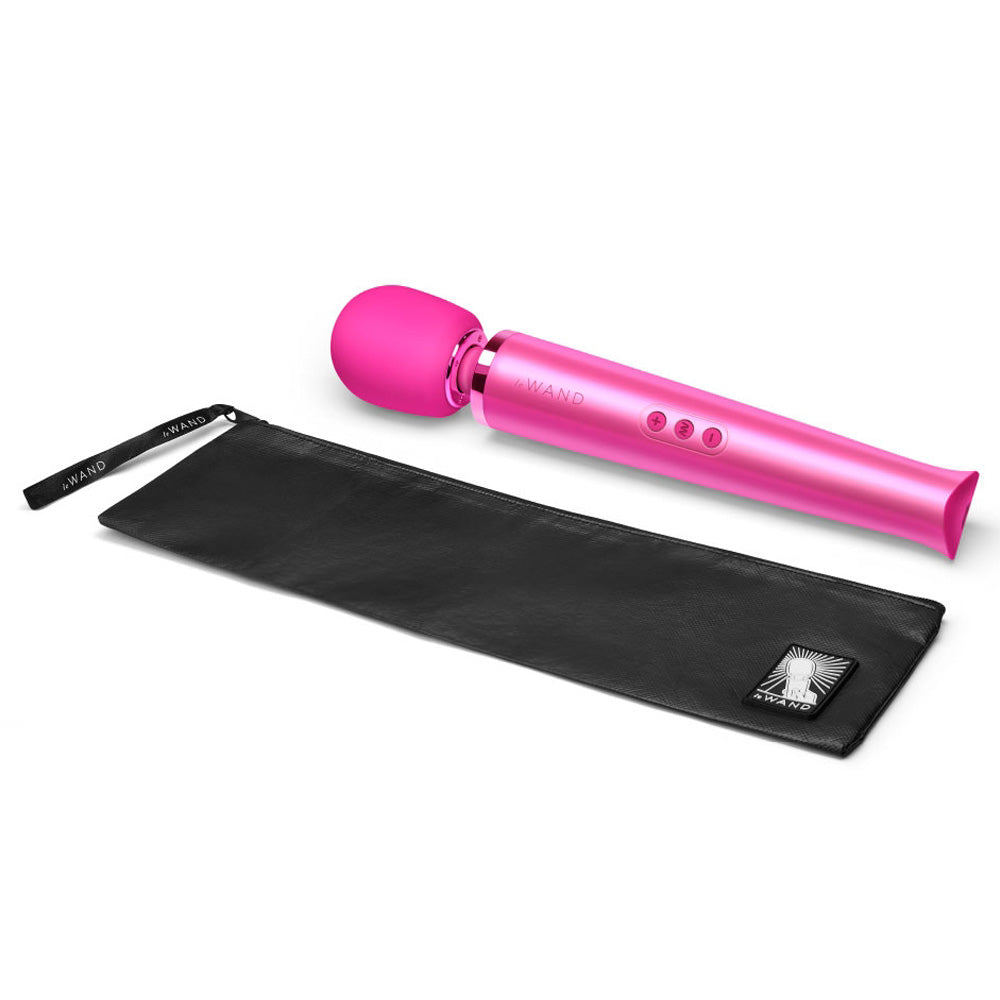 A magenta vibrating massager lays next to its black case.