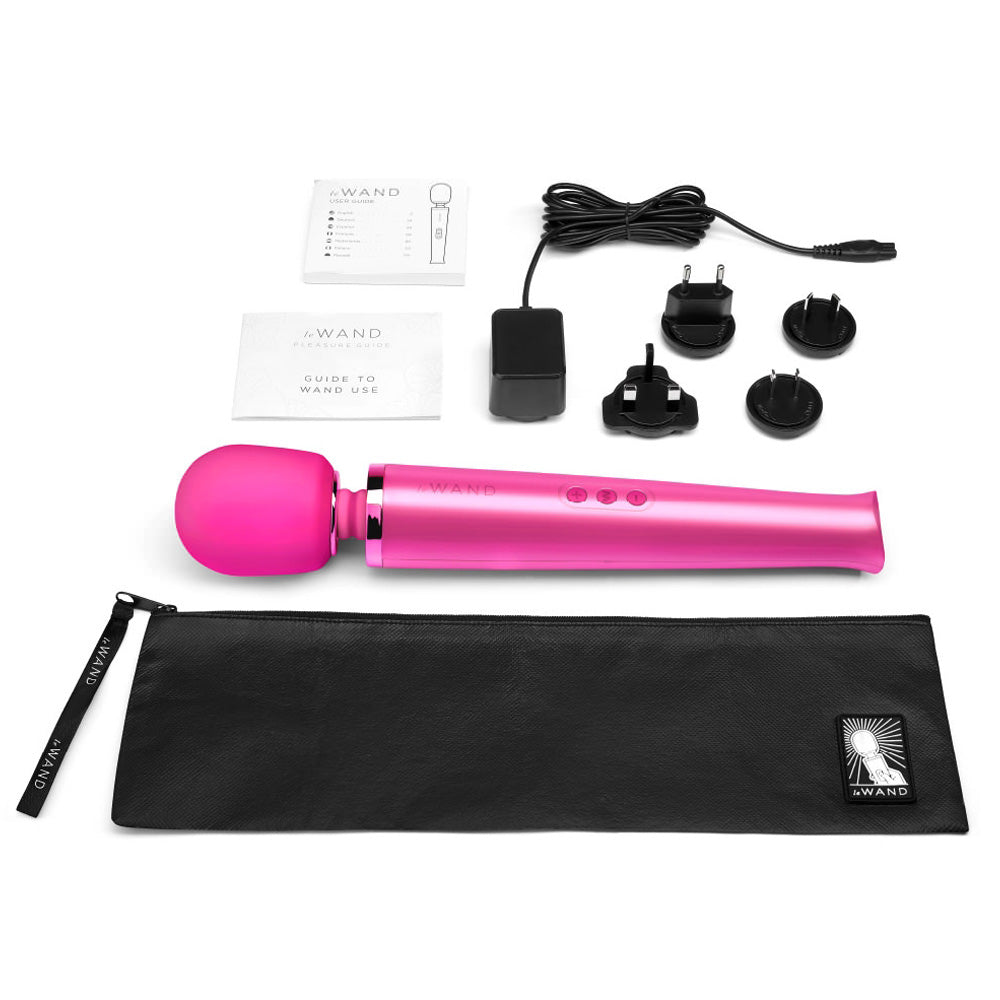 A vibrating massager lays next to its wall plus, charging cord, black case and instruction manual.