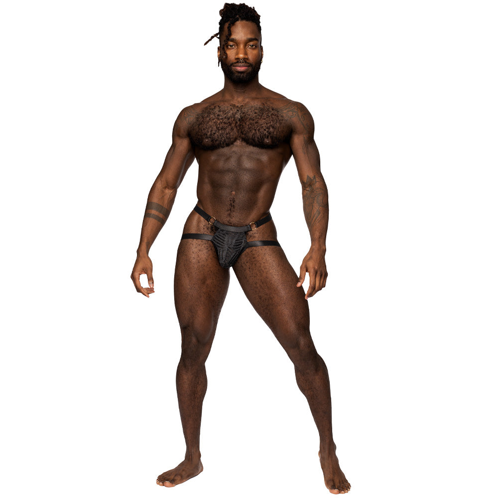A male lingerie model wearing a cutout jockstrap in black sheer mesh with his package covered and his hips exposed.
