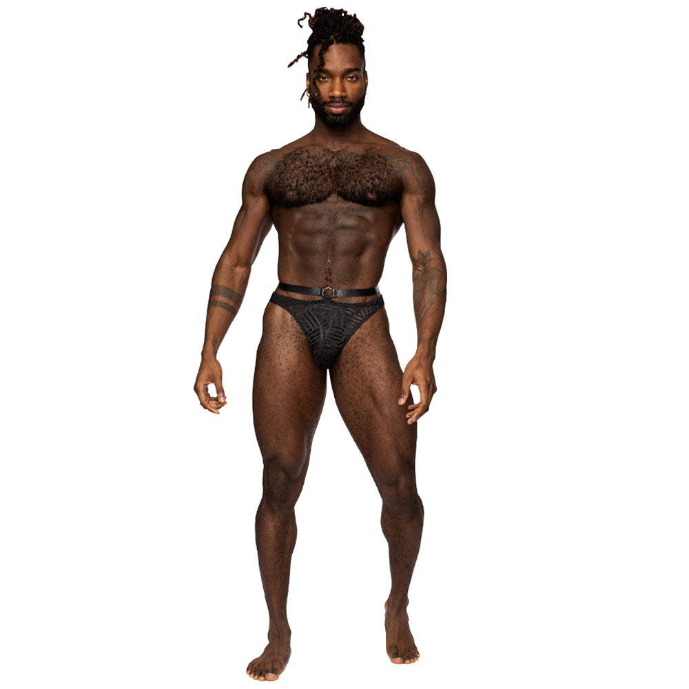 A male model poses wearing a sheer mesh thong with a geometric stripe pattern and strappy waistband in black.