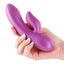 A hand model holds a ribbed metallic pink rabbit vibrator.