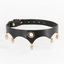 A black faux leather collar with a pointed, curved hem and pearls dangling from gold hardware. 