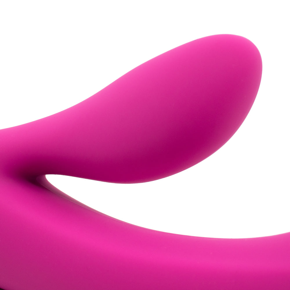 A close up of a dark pink silicone rabbit vibrator's clitoral stimulator against a white background. 