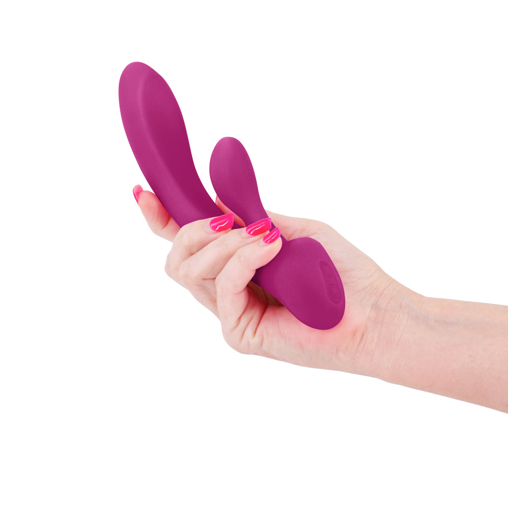 A manicured hand holds a dark pink silicone G spot rabbit vibrator for scale.