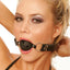 A female model wears a black breathable ball gag in black with adjustable buckles.