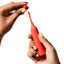 A hand model holds a red, cylindrical wand-shaped clitoral vibrator while showing how to attach its spherical head.