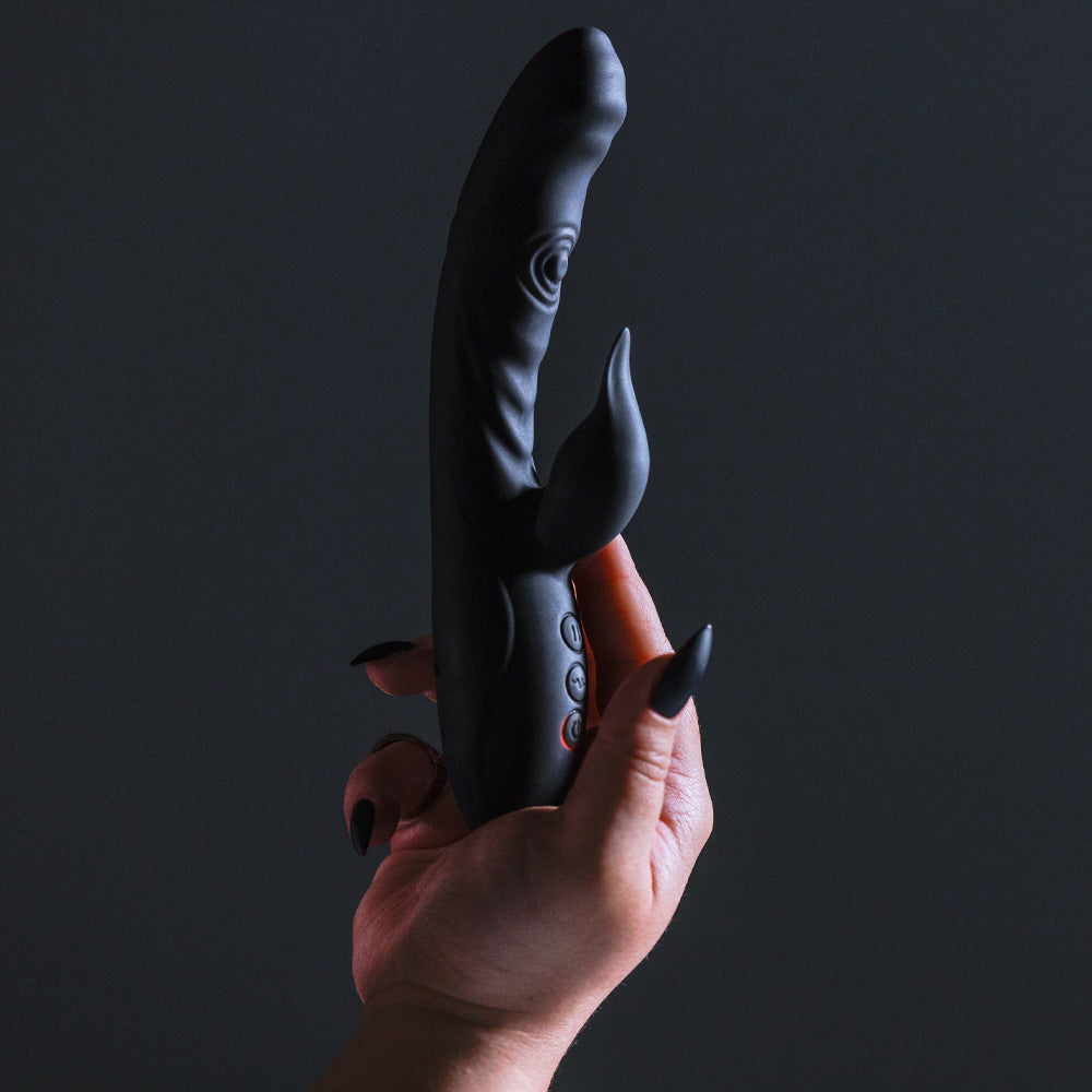 Close up of a models hand holding a Sexyland Rumble thumping G spot rabbit vibrator in black.