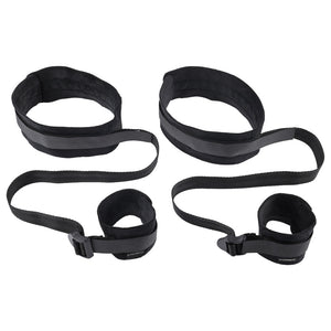 A pair of black thigh and wrist cuff restraints lays flat on a white background. 