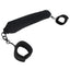 A black padded velvet bondage bar with velvet handcuffs attached at either side lays on a white backdrop. 