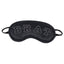 A satin eye mask in black with the word BRAT embroiled on it in white lays against a white backdrop. 
