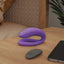 A We-Vibe Sync O secure fit couples vibrator sits on a bedside table next to its remote control and phone.