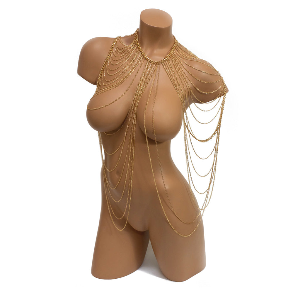 A mannequin wears a gold draped shoulder body chain against a white backdrop.