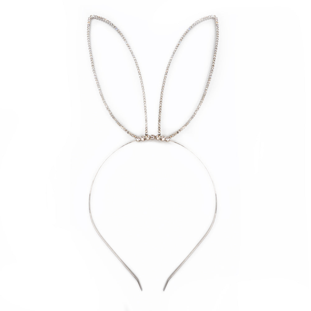 Silver metal headband with rabbit ears encrusted with diamanté’s lays flat on a white backdrop.