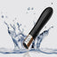 A mini silicone bullet vibrator in black is shown dropped in water showcasing its waterproof design.
