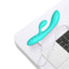 A turquoise g-spot rabbit vibrator is shown attached to its charging cord on top of a laptop.