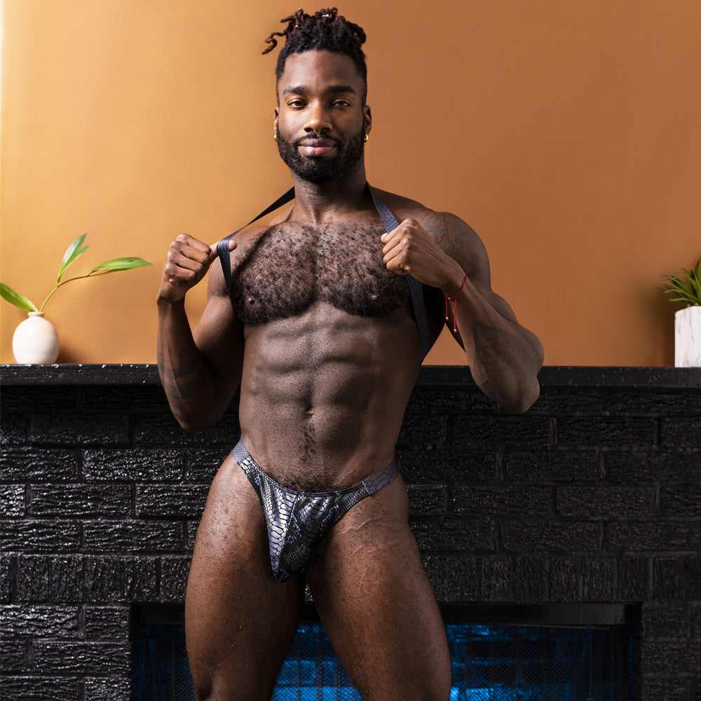 Male Power S'Naked Snakeskin Print Shoulder Sling Harness Thong has a metallic snakeskin print w/ a thong-cut rear, shoulder straps & a behind-the-neck sling for support that accentuates your torso! Black & blue. Editorial.